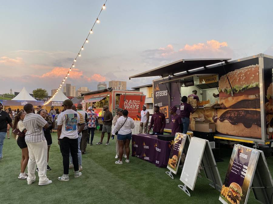 Crowd gathered at the Flame Grilled Events trailer at golden hour
